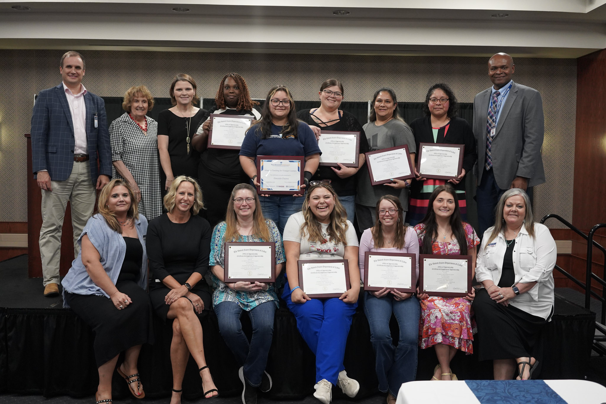 Group photo of graduates holding certificates during a celebration event.