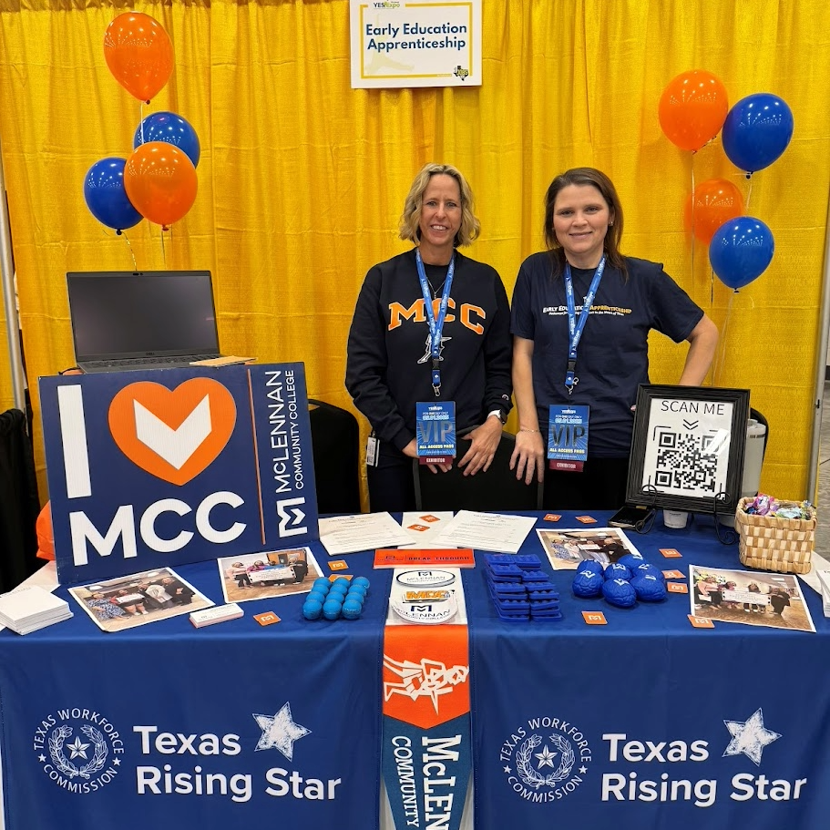 Two women stand behind a booth at a career fair, promoting the Early Education Apprenticeship program with signage and promotional materials, including a "SCAN ME" QR code.