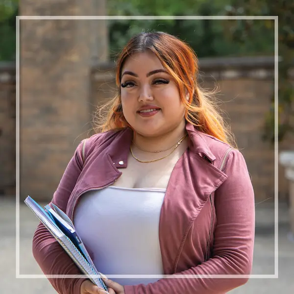 MCC student Rosemary Marquez smiles while holding a binder on campus.