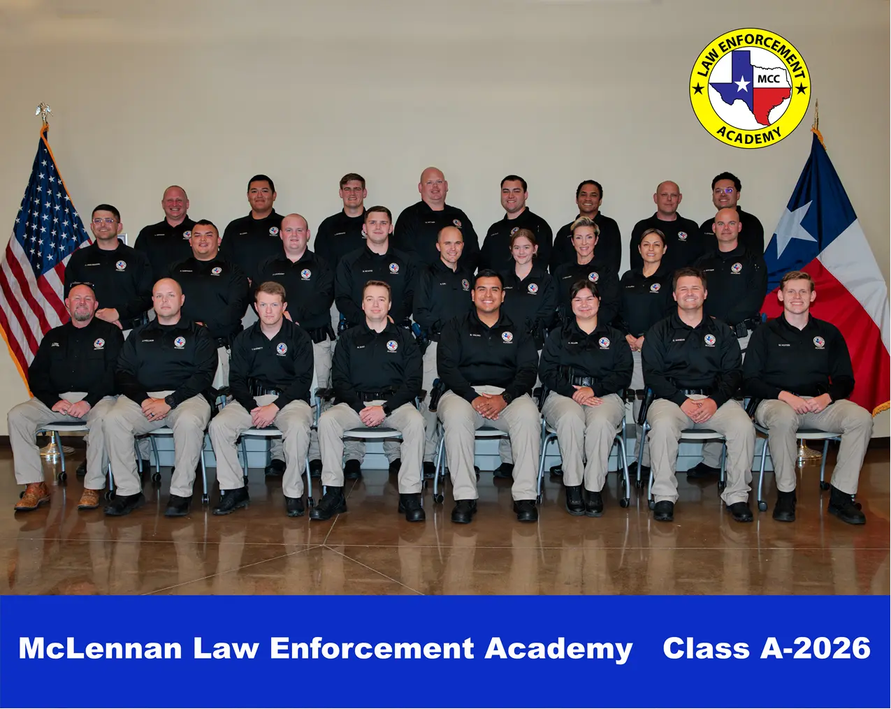 Group portrait of McLennan Law Enforcement Academy Class A-2026 in uniform, posed indoors between U.S. and Texas flags with the academy seal in the corner.