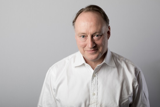 Professional portrait of a middle-aged man wearing a white button-up shirt, with a neutral background.
