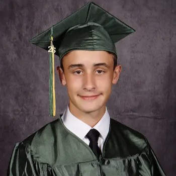 Studio portrait of a young person wearing a green graduation cap and gown with a white shirt and black tie.